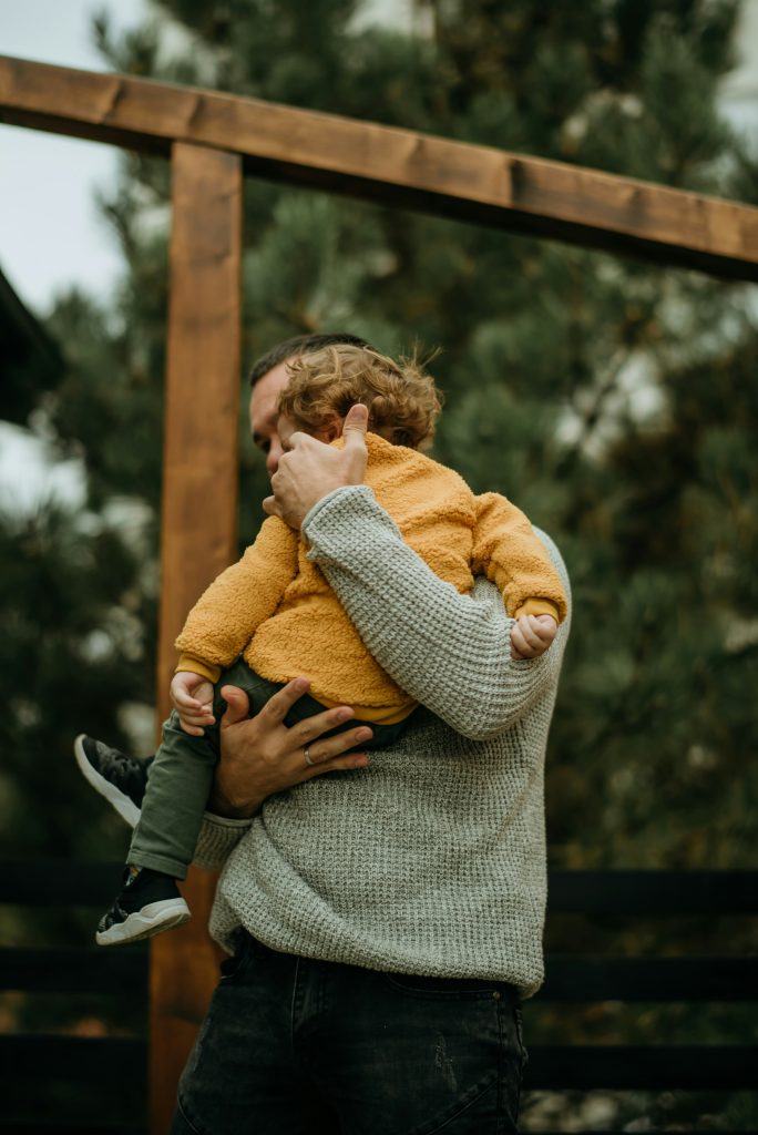 Papà che tiene in braccio il figlio all'aperto