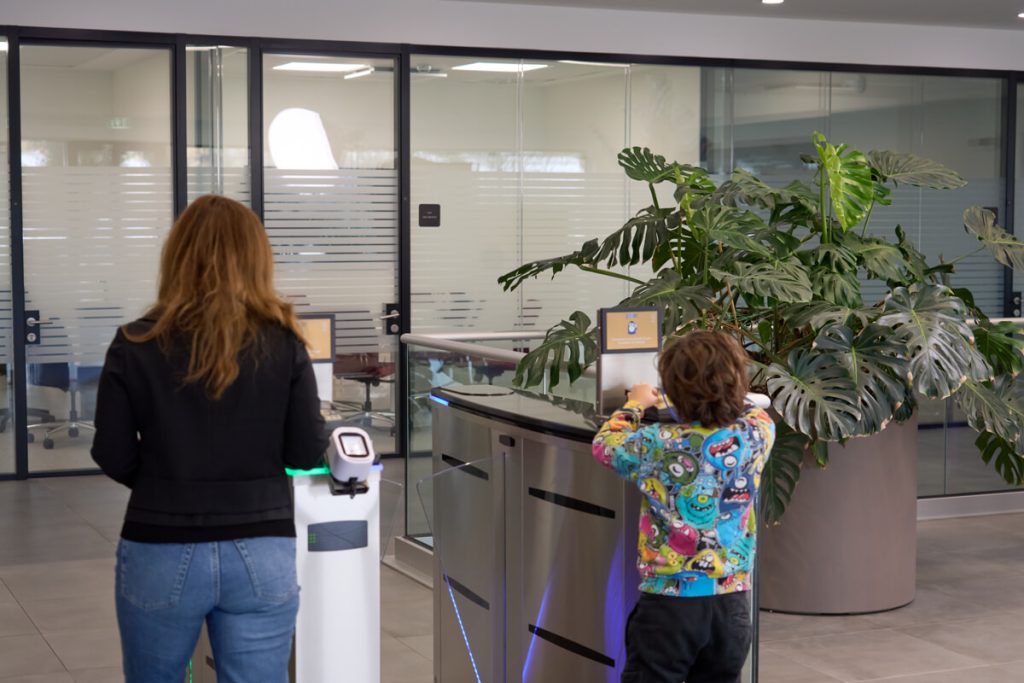 Donna e bambino di spalle passano attraverso i tornelli all’ingresso di un ufficio moderno.