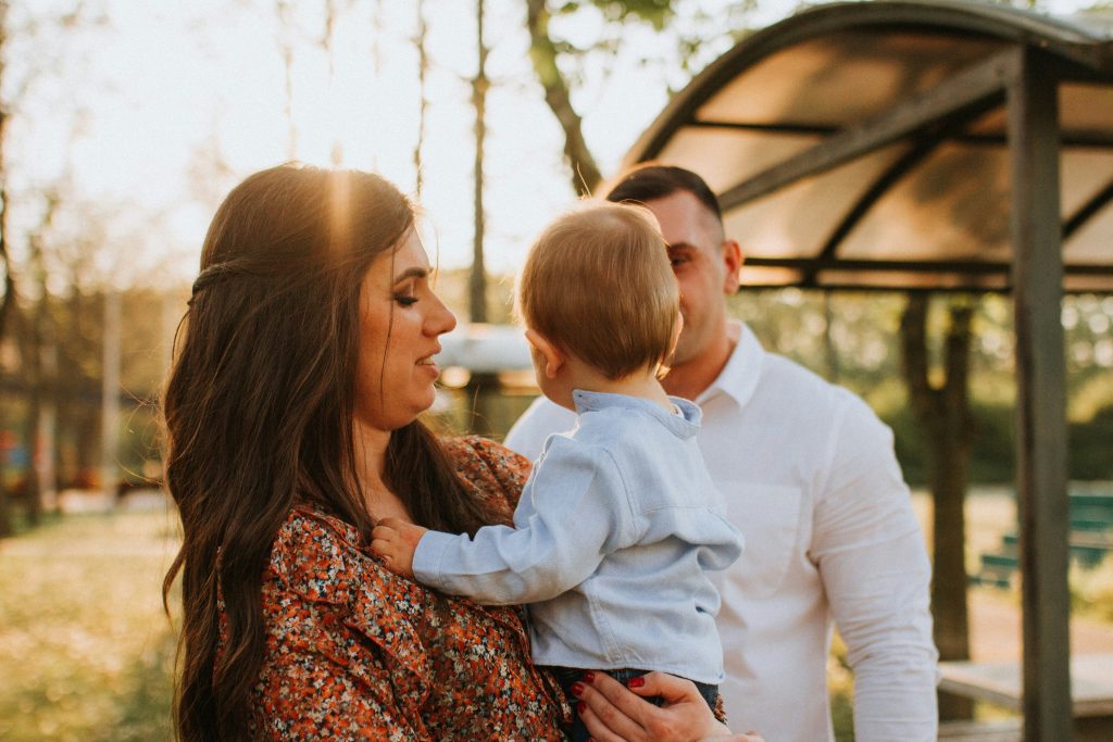 Papà e mamma con il braccio il figlio, all'aperto.