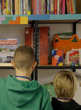 Due bambini osservano una libreria con giochi da tavolo e libri colorati.