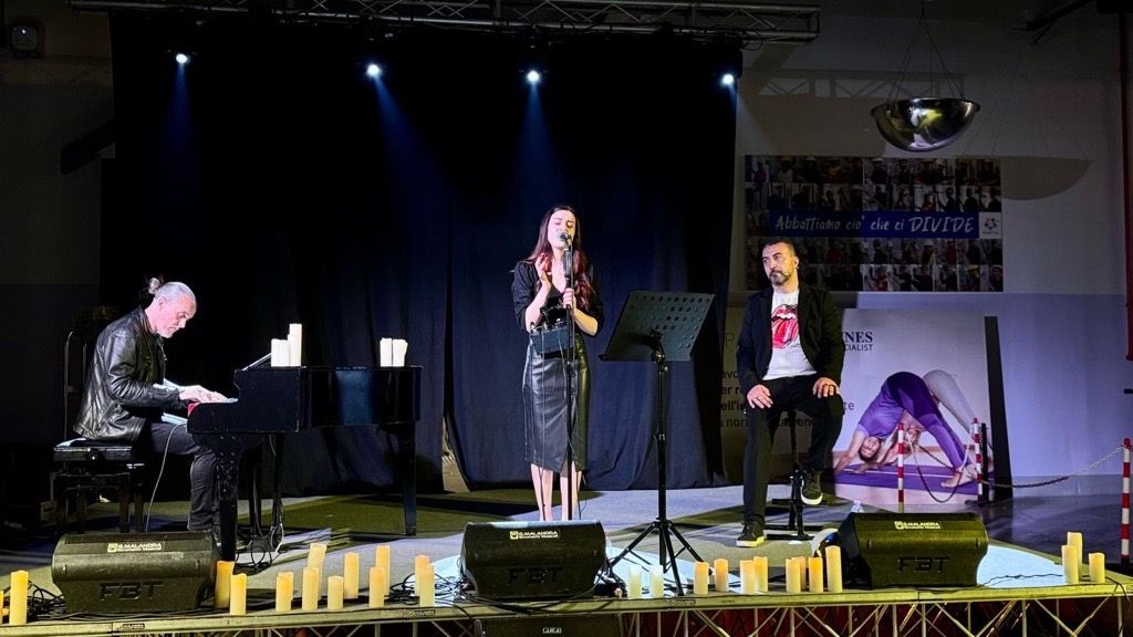 Un pianista e cantante si esibiscono su un palco illuminato.