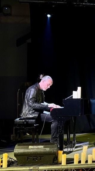 Un musicista suona il pianoforte su un palco illuminato.